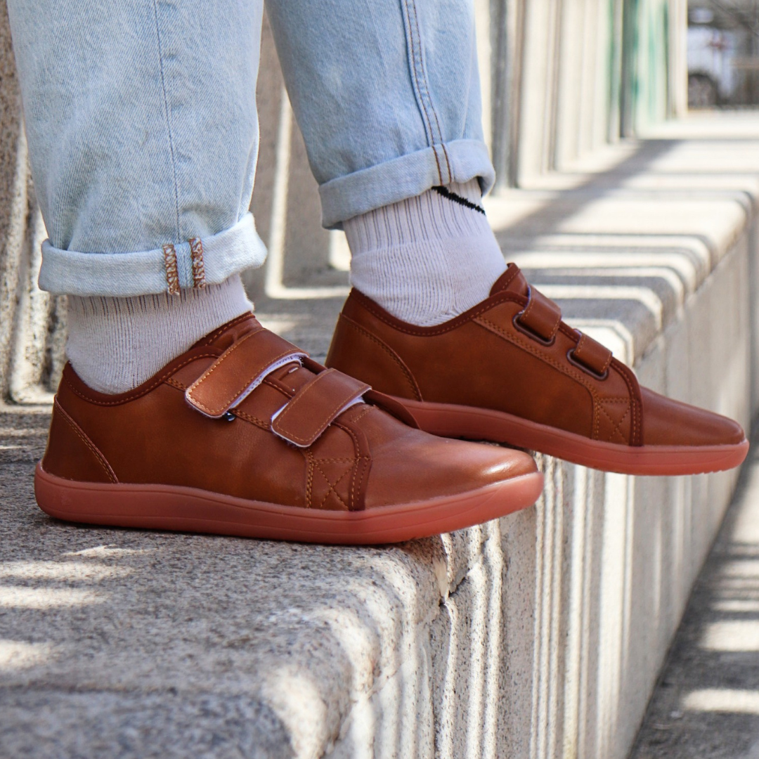 brown barefoot shoes with velcro with white socks and jeans on light grey stairs