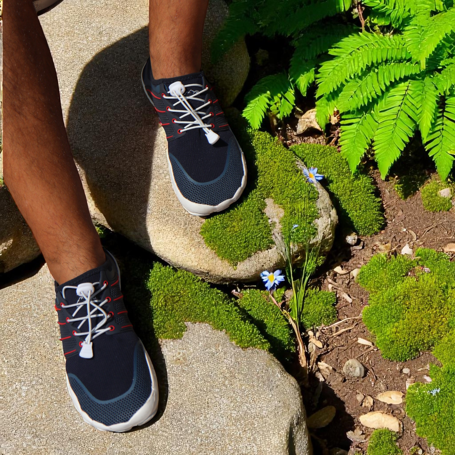 blue barefoot shoes with white laces and sole on rocks with green herbs