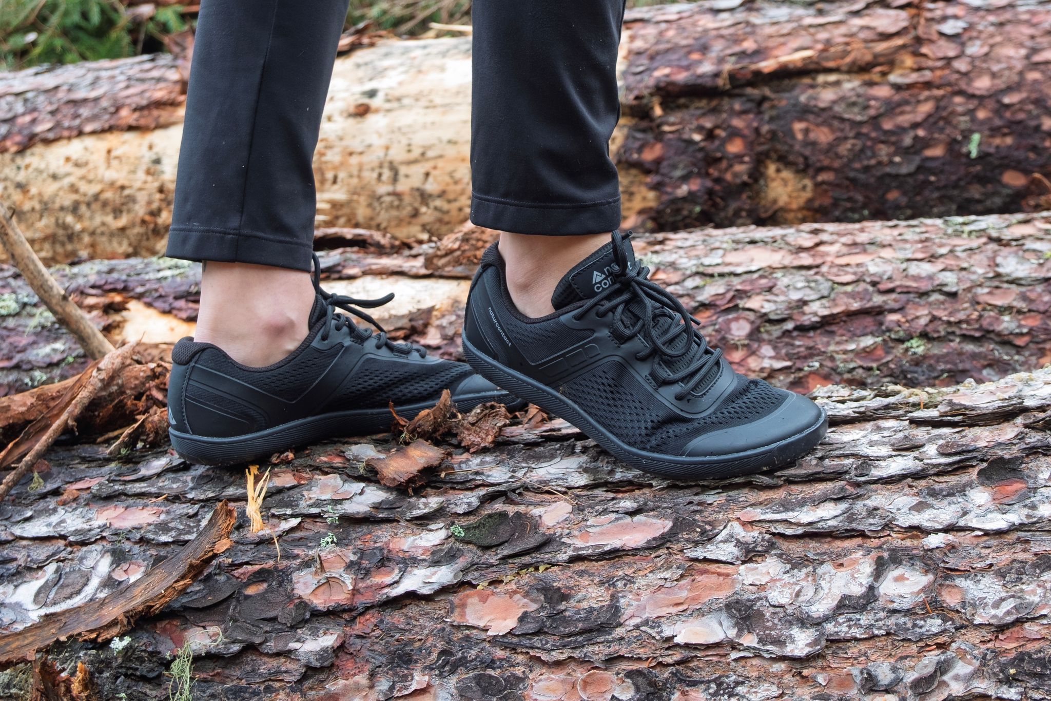 black barefoot shoes with naturcontact logo on a tree horizontal