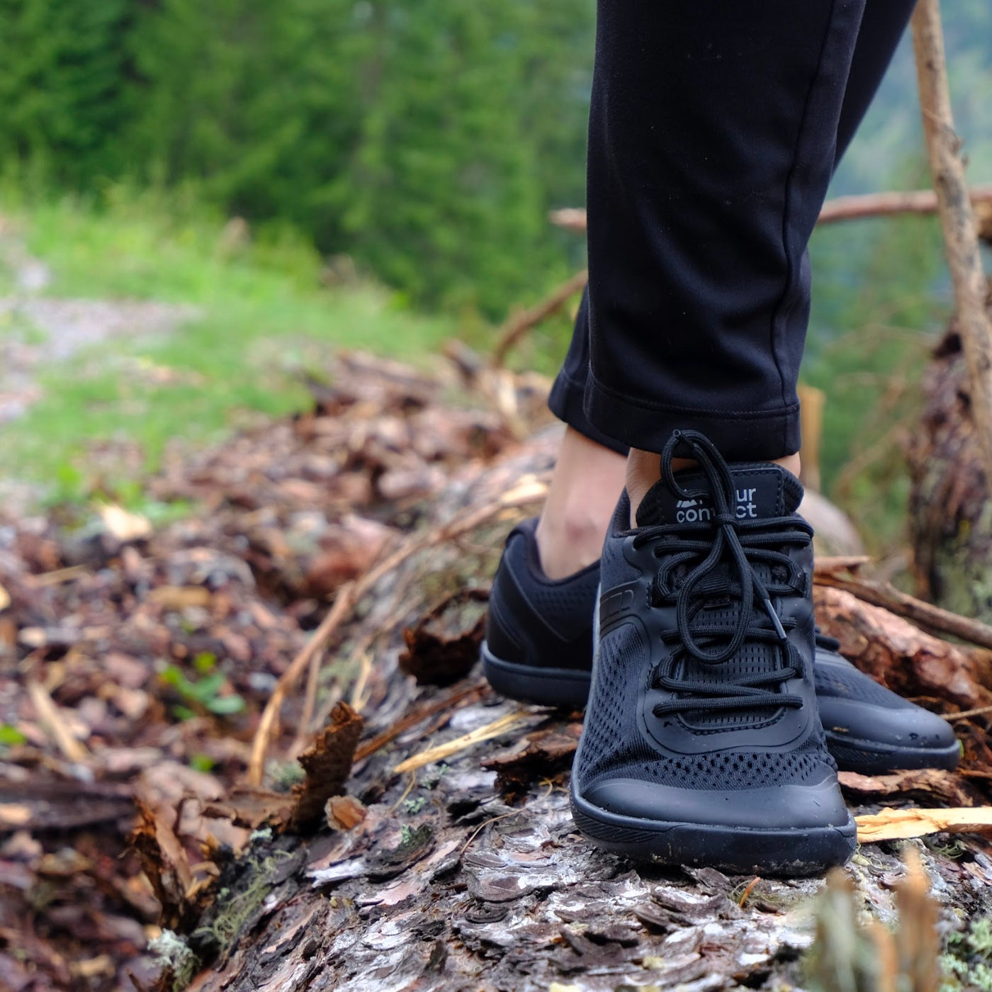 black barefoot shoes with mesh upper on a log in autumn