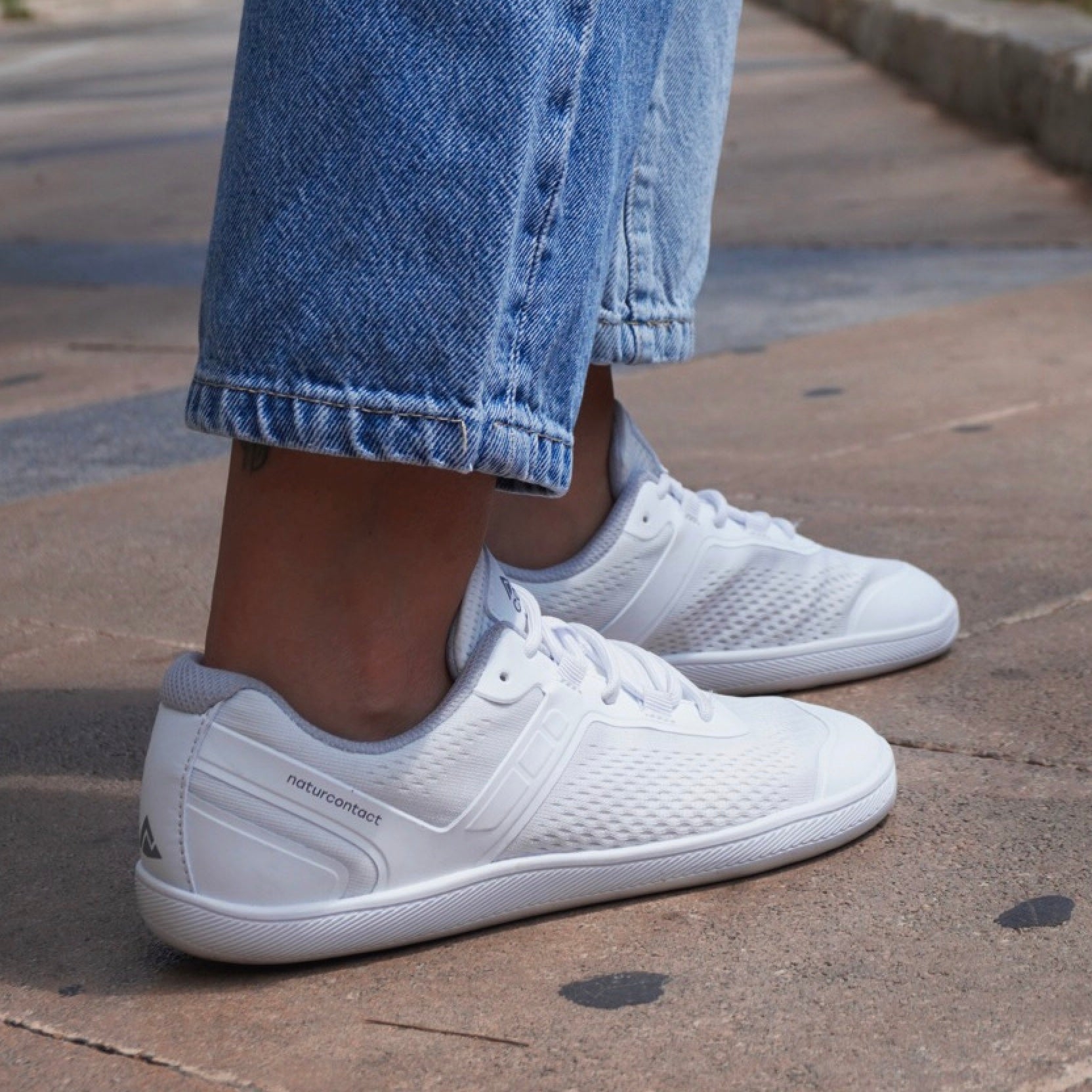 white barefoot shoes trainers with naturcontact logo with jeans on pavement