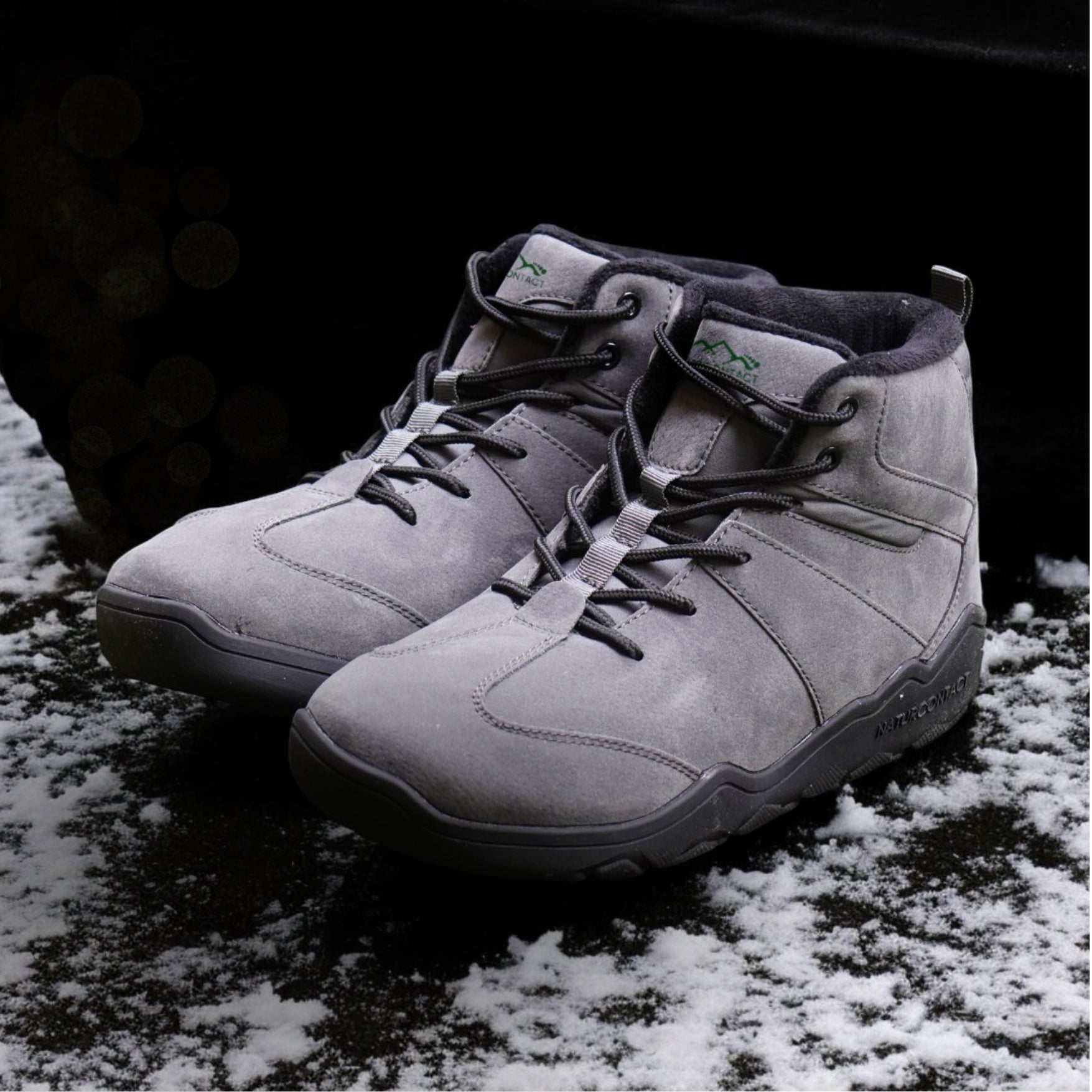 grey suede winter shoes boots with black laces with snowy terrain