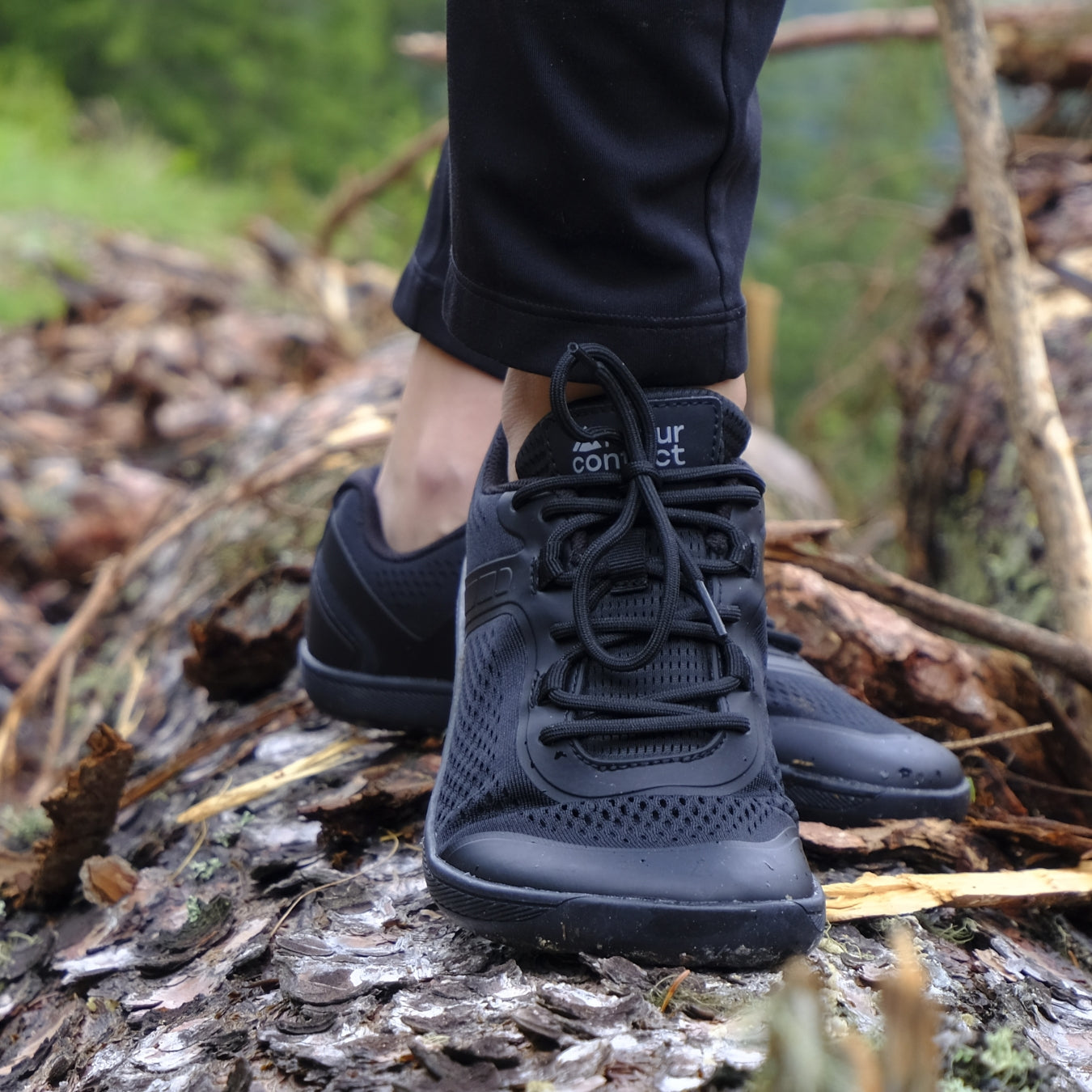 Black hiking boots on a forest floor
