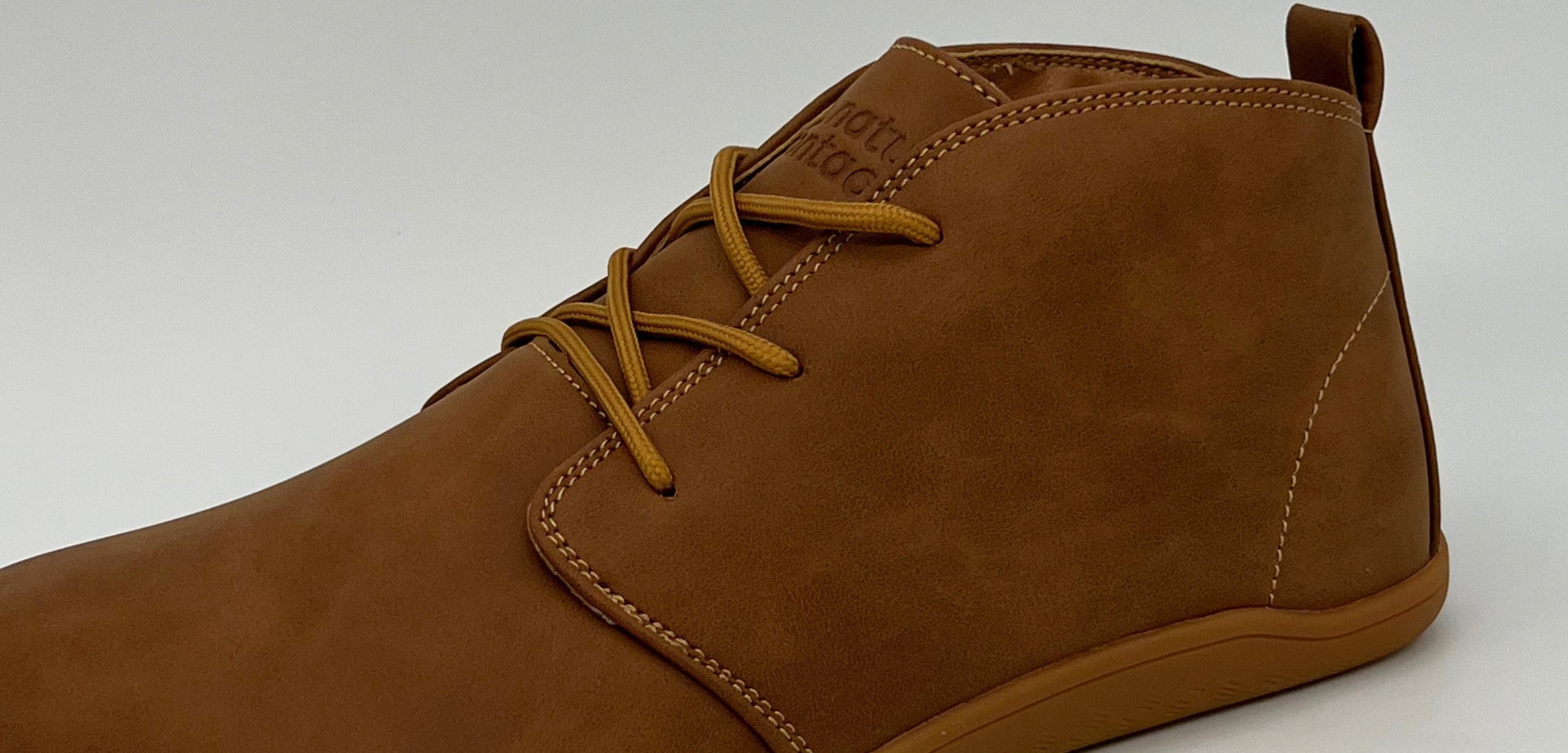 Brown leather boot with yellow laces on a white background
