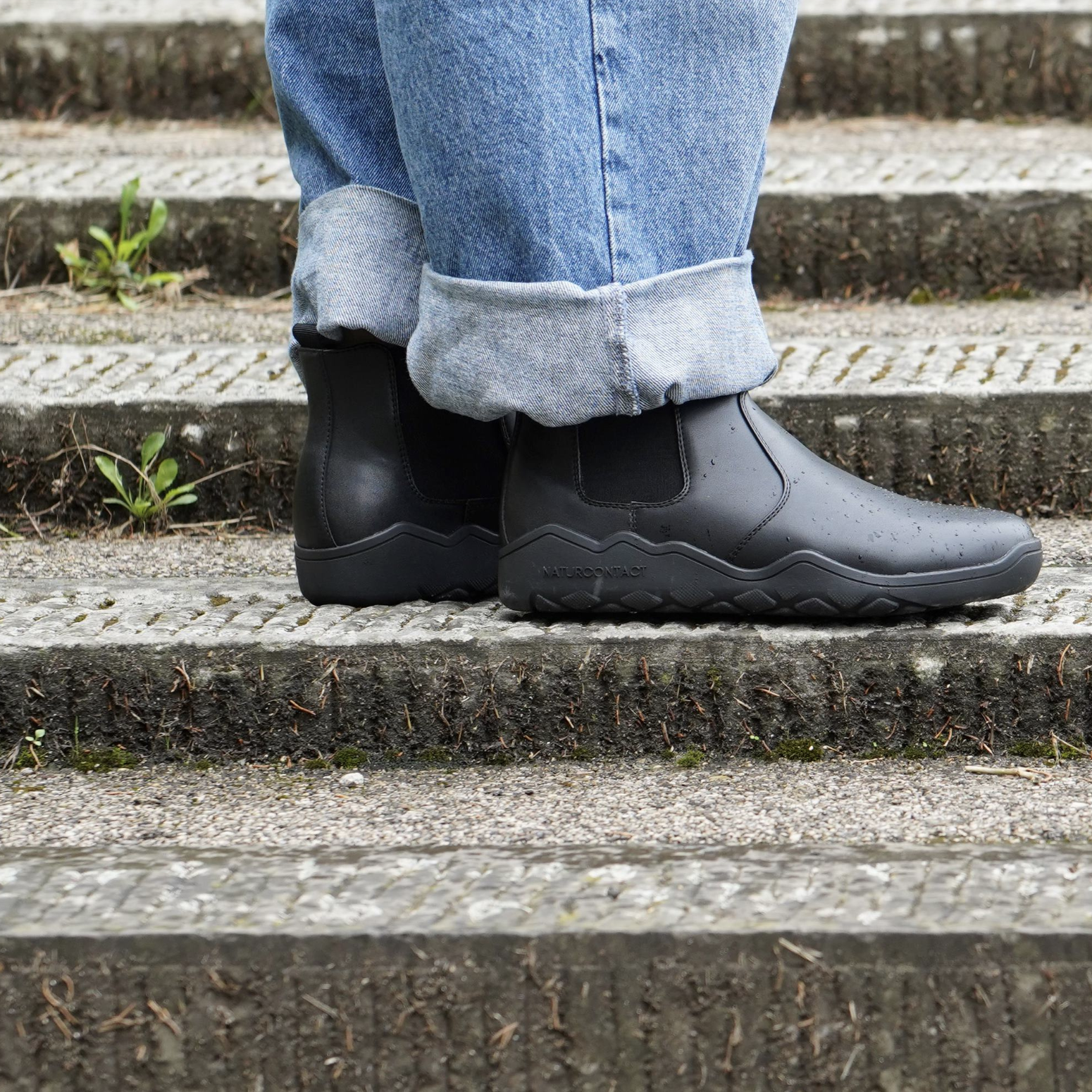 side view of black barefoot chelsea minimalisdt boots on stairs