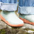 detail of green barefoot chelsea boots from top with orange sole on a rock