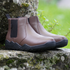 side view of brown minimalistic barefoot chelsea boots on a rock