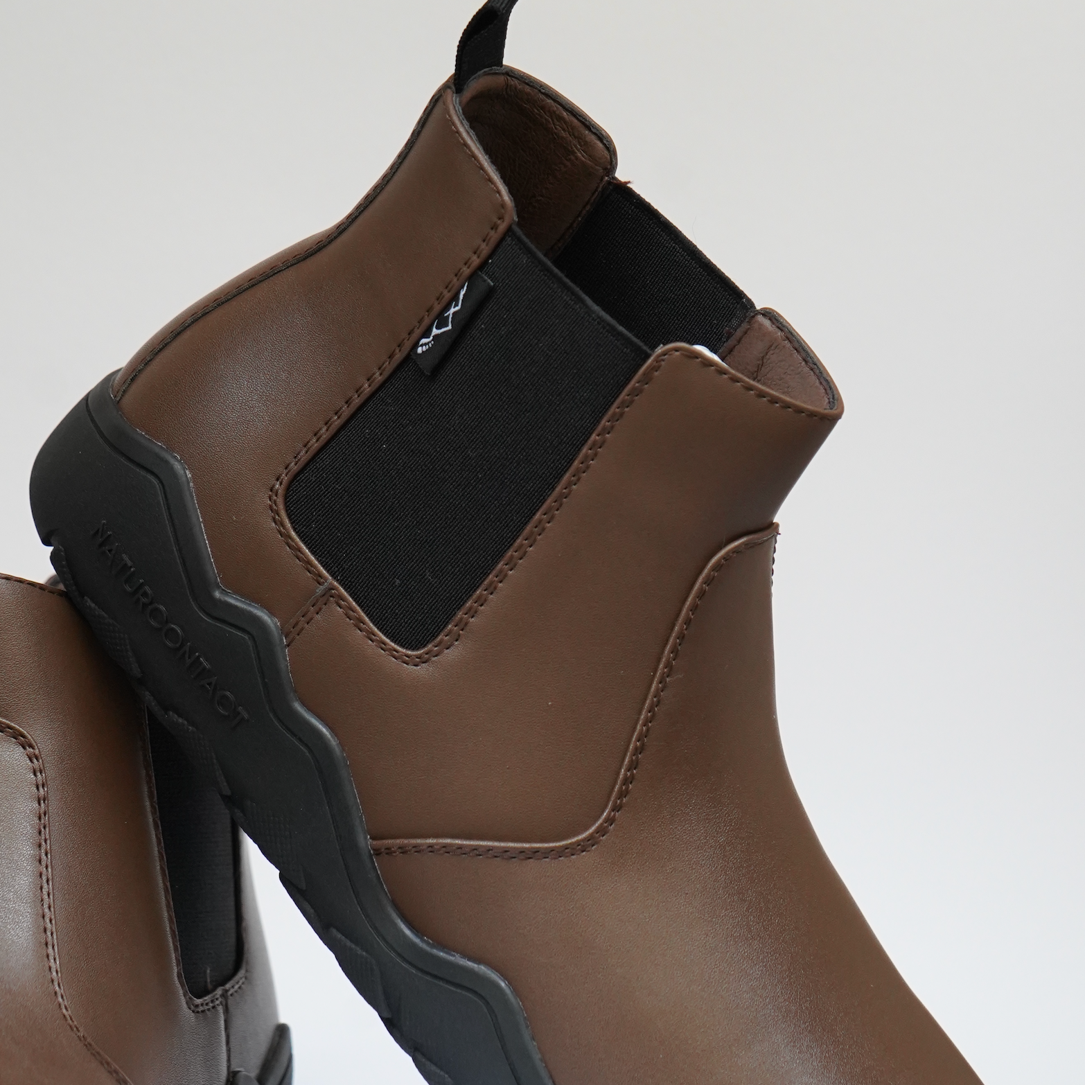 detail of closure of brown barefoot chealsea boots in studio