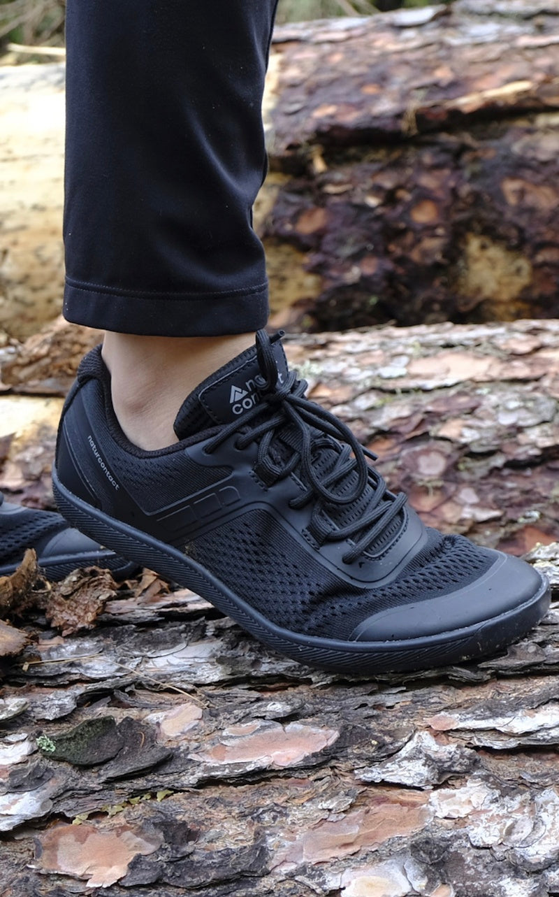 Person wearing black barefoot shoes trainers on a wooden surface