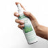 Hand holding a bottle of naturcontact spray water and stain repellent spray on a white background