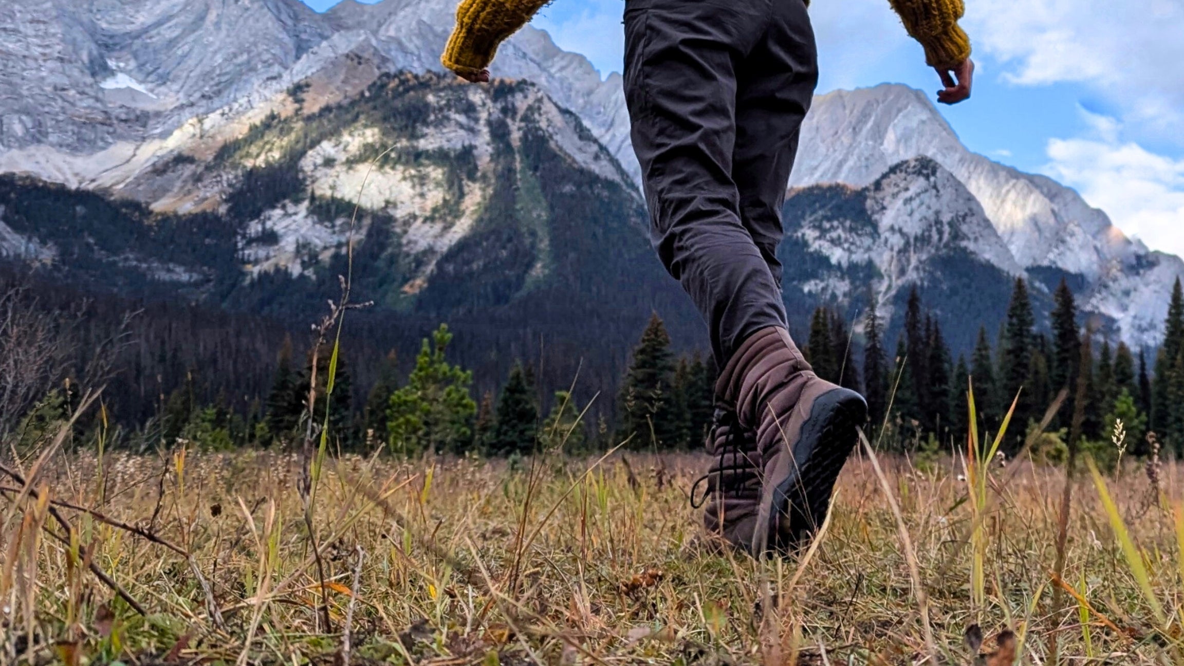 Person hiking in minimalist boots on a mountain meadow, practicing natural movement in the wilderness