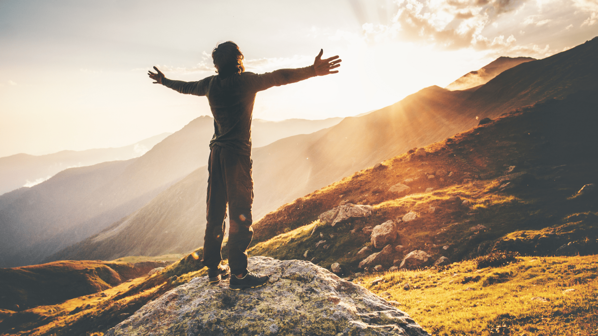 person looking with wide open arms a sunrise on the mountains