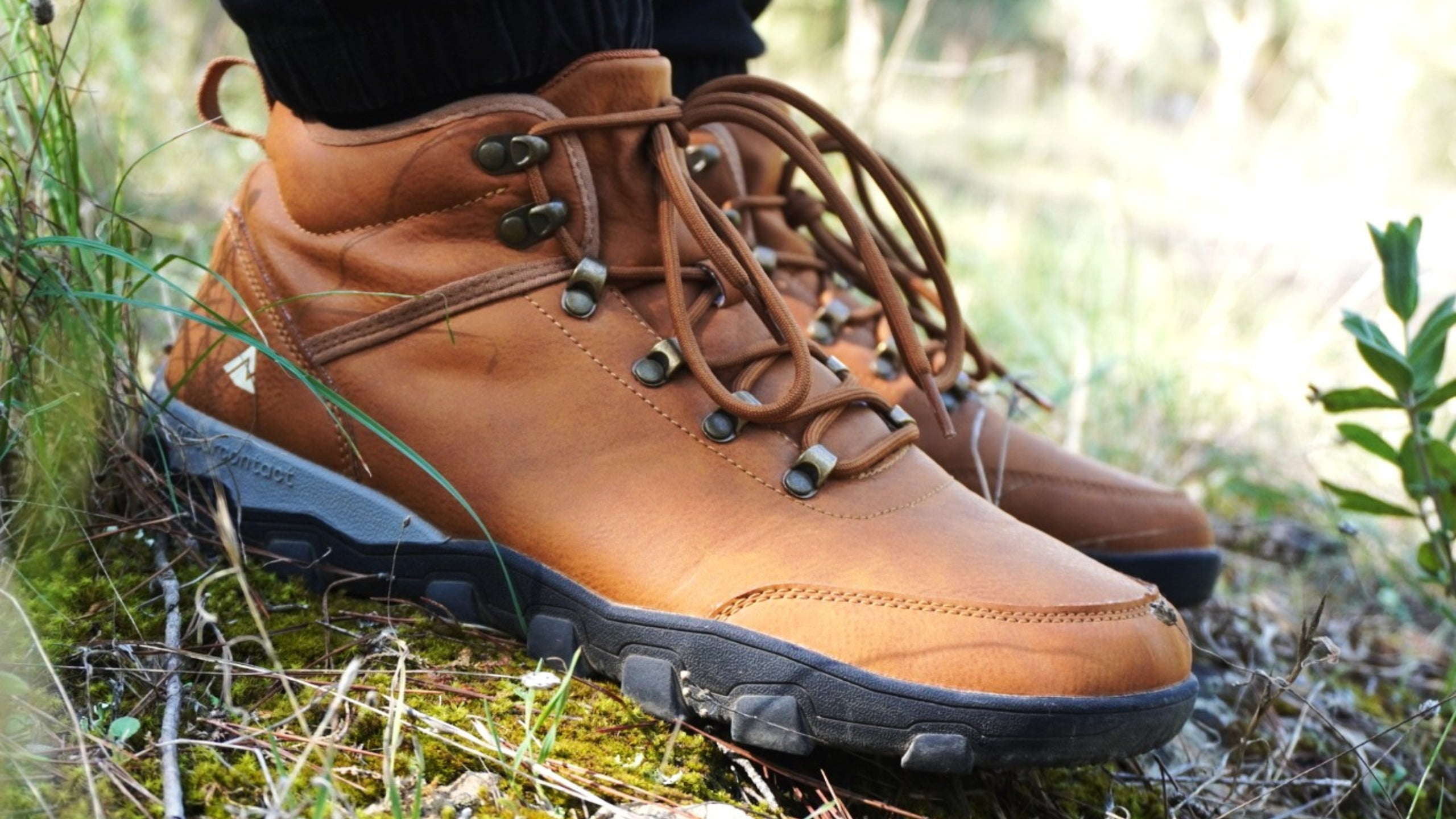 Close-up of brown Naturcontact eco-friendly hiking boots on a forest trail, showing durable sole and natural leather texture