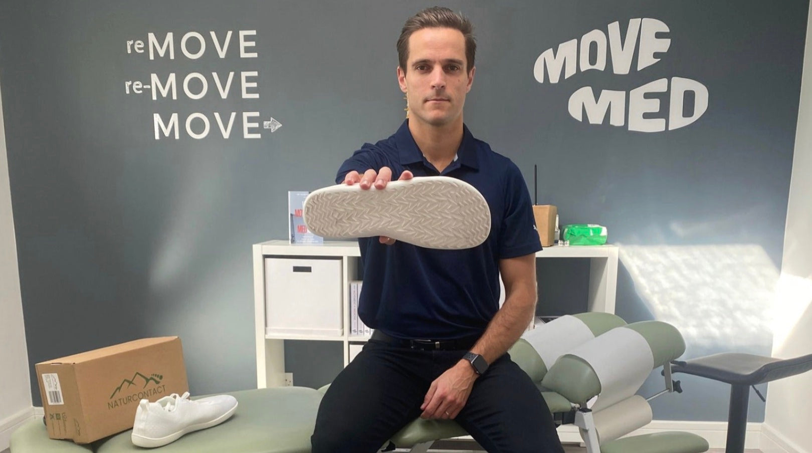 podiatrist holding naturcontact barefoot shoes in his studio
