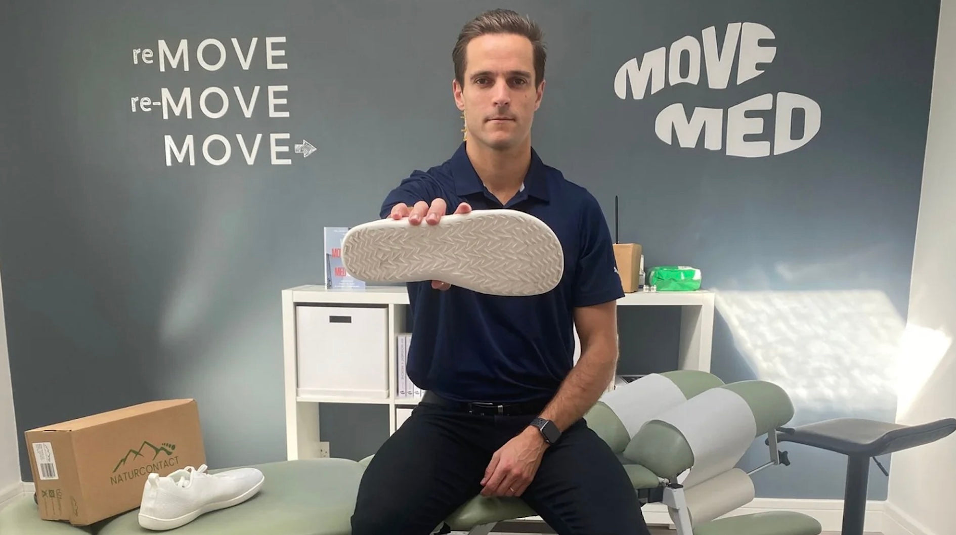 podiatrist holding naturcontact barefoot shoes in his studio