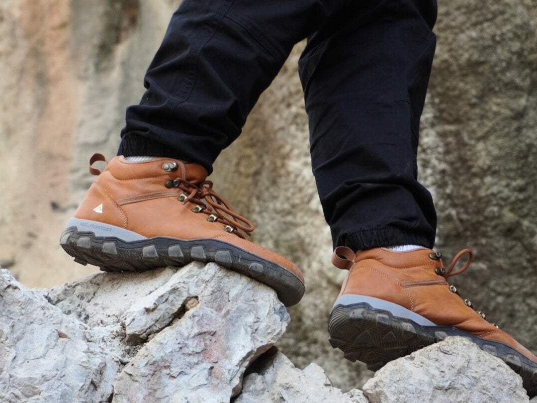 Person wearing tobacco hiking barefoot boots on rocky terrain