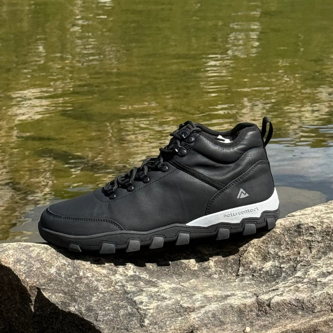Black hiking barefoot shoe on a rock with water in the background