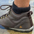 Brown hiking barefoot boot with a brand logo worn by a person on a natural background