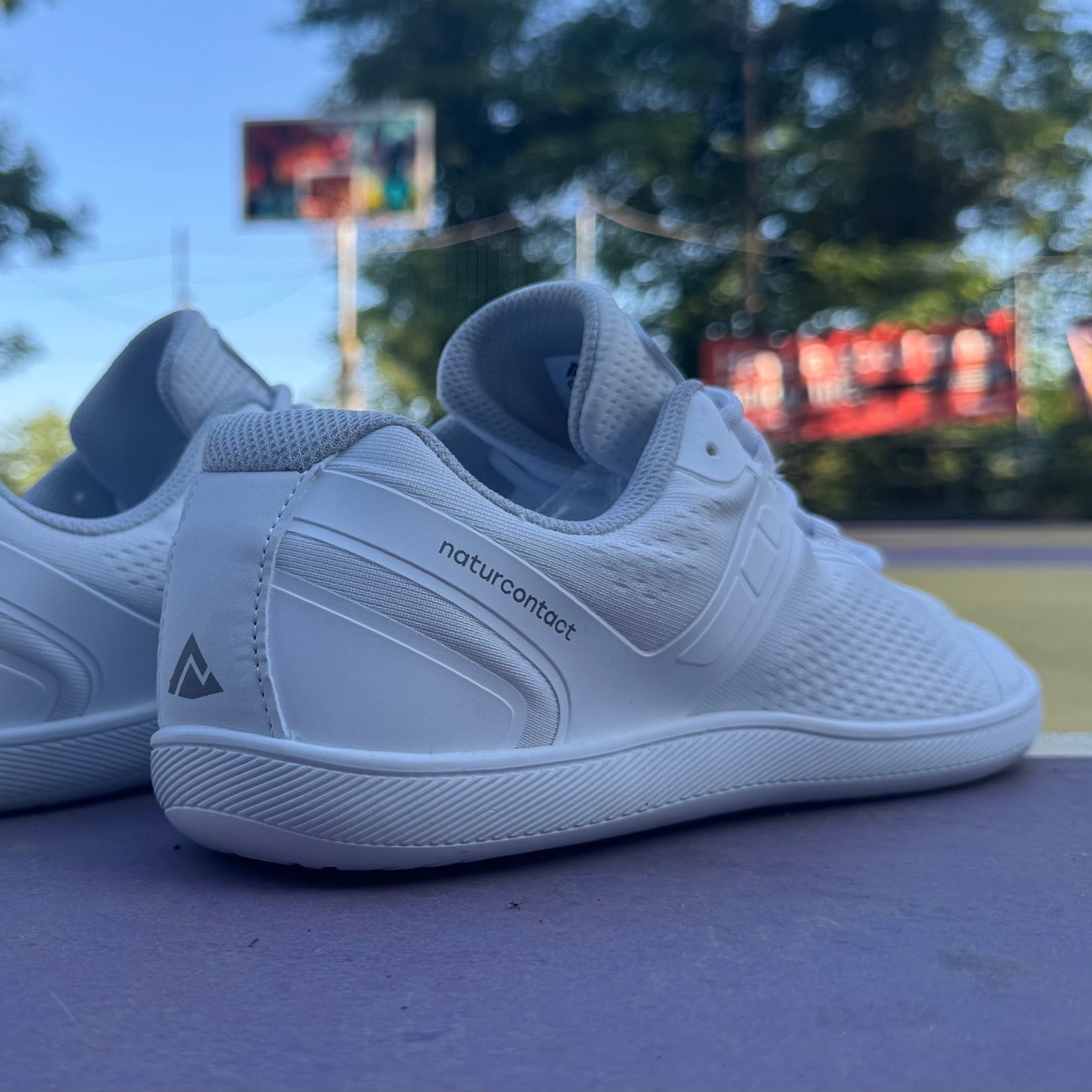 Back view of white Daily Barefoot shoes in an outdoor sports park 