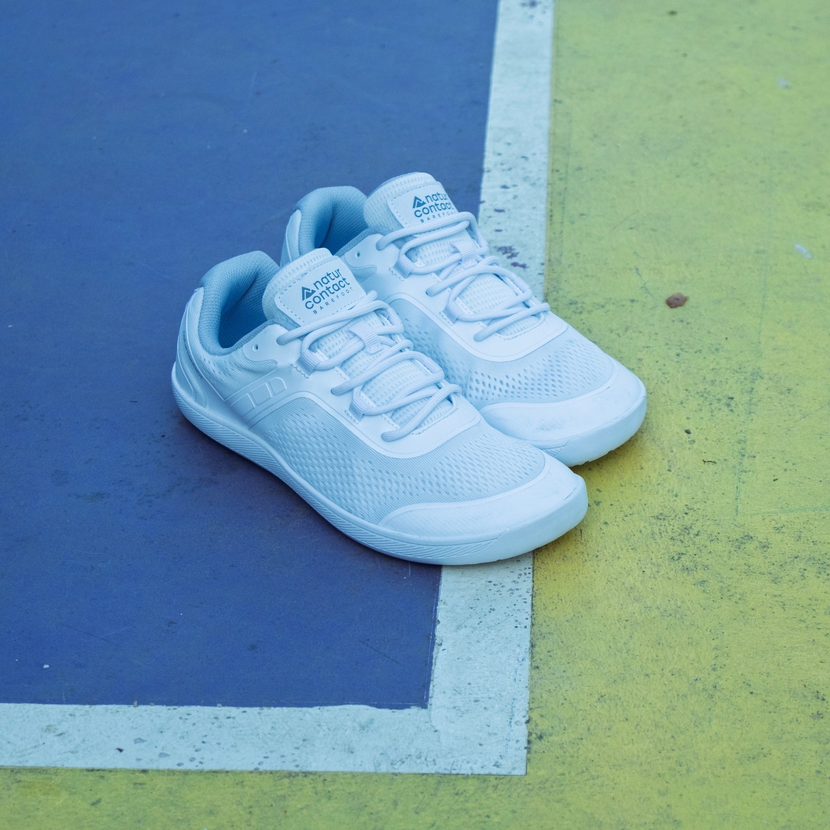 Pair of White Daily Barefoot shoes in an outdoor sports park