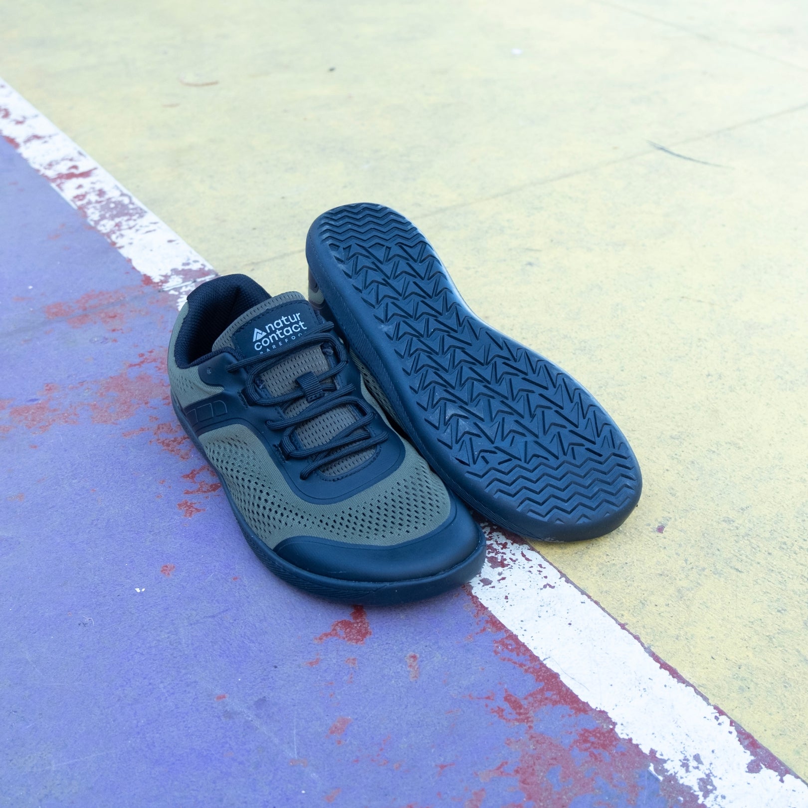 Military Green Barefoot shoes with basketball on sports court, showing sole details