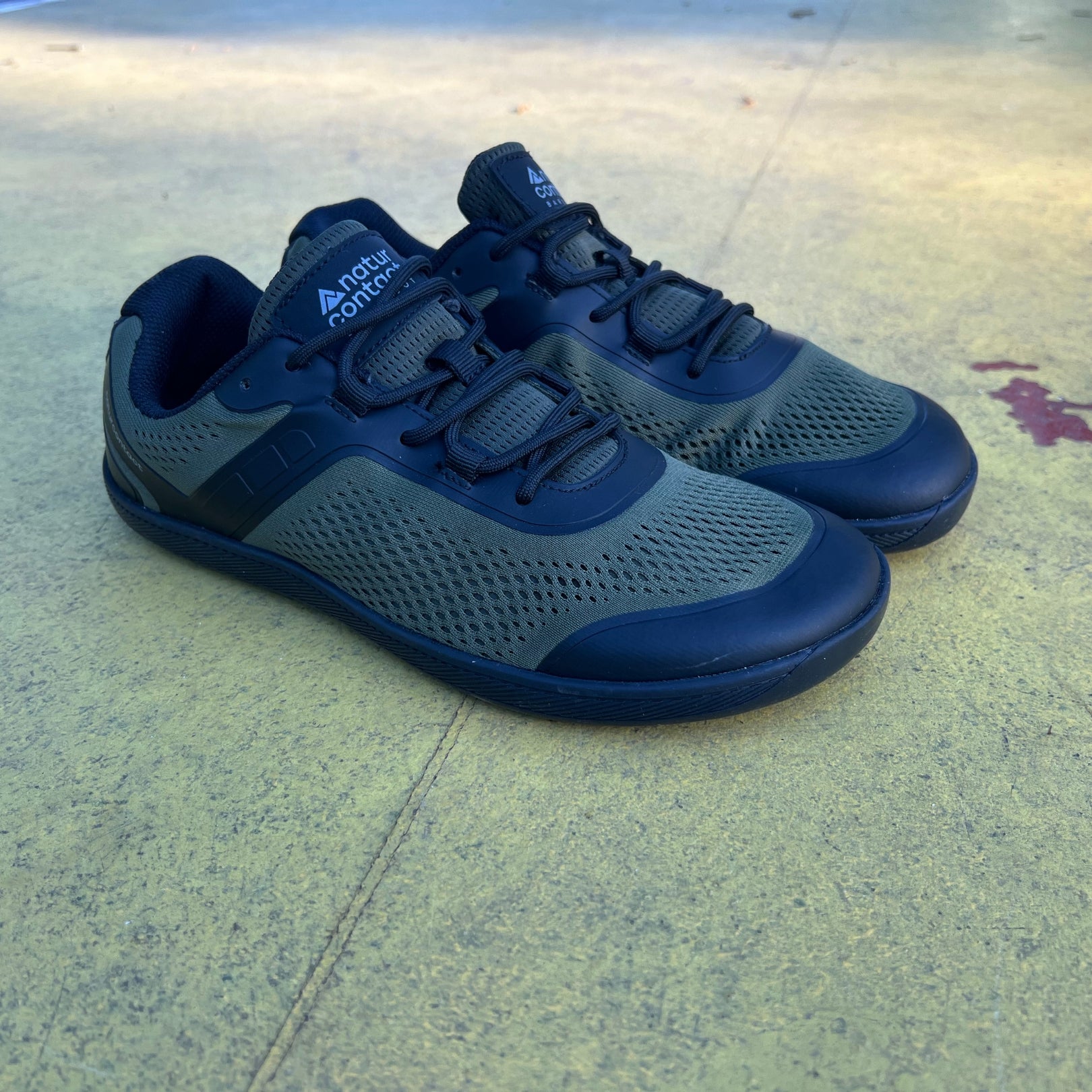 Military green Barefoot shoes on a paved sports court