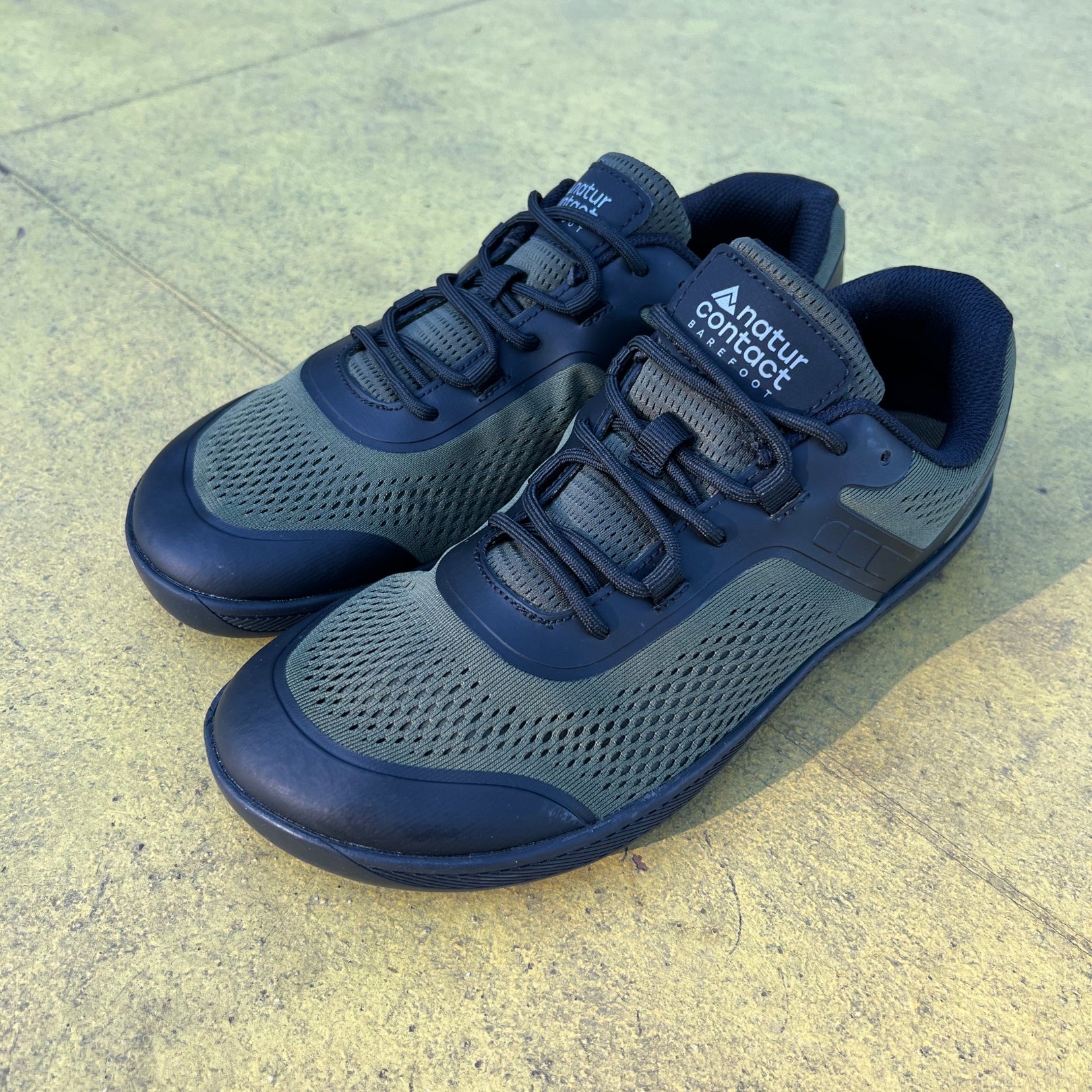 Military green Barefoot shoes on a paved sports court