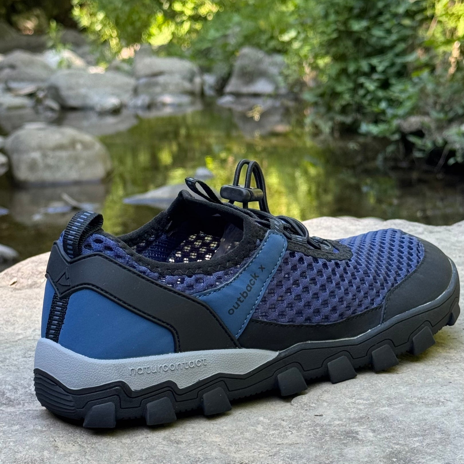 Blue hiking barefoot shoe on natural rock landscape, back detail
