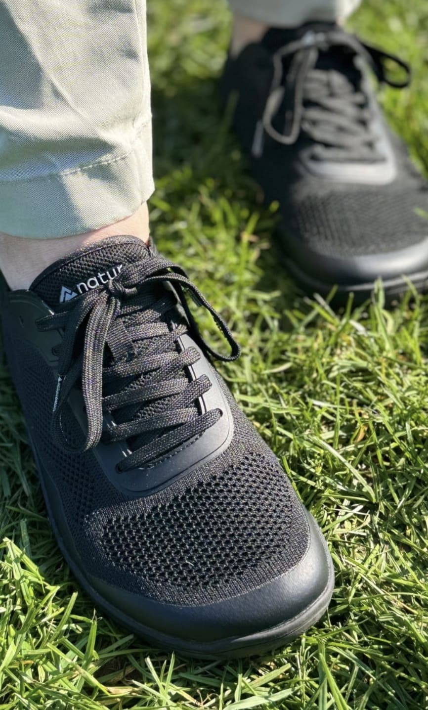 Black athletic barefoot shoes on grass with a visible brand naturcontact logo