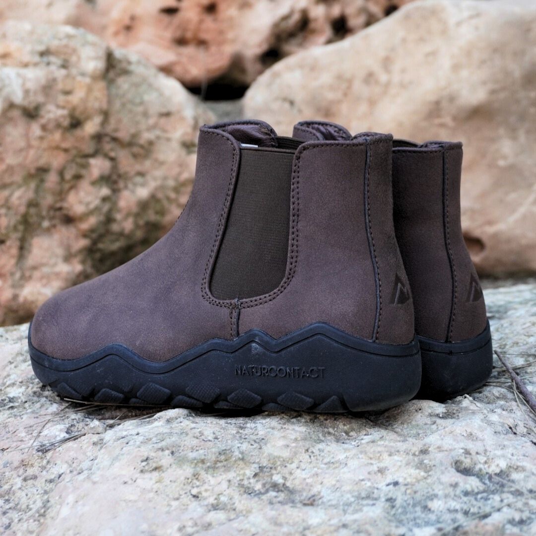 Pair of brown boots with black soles on a rocky surface