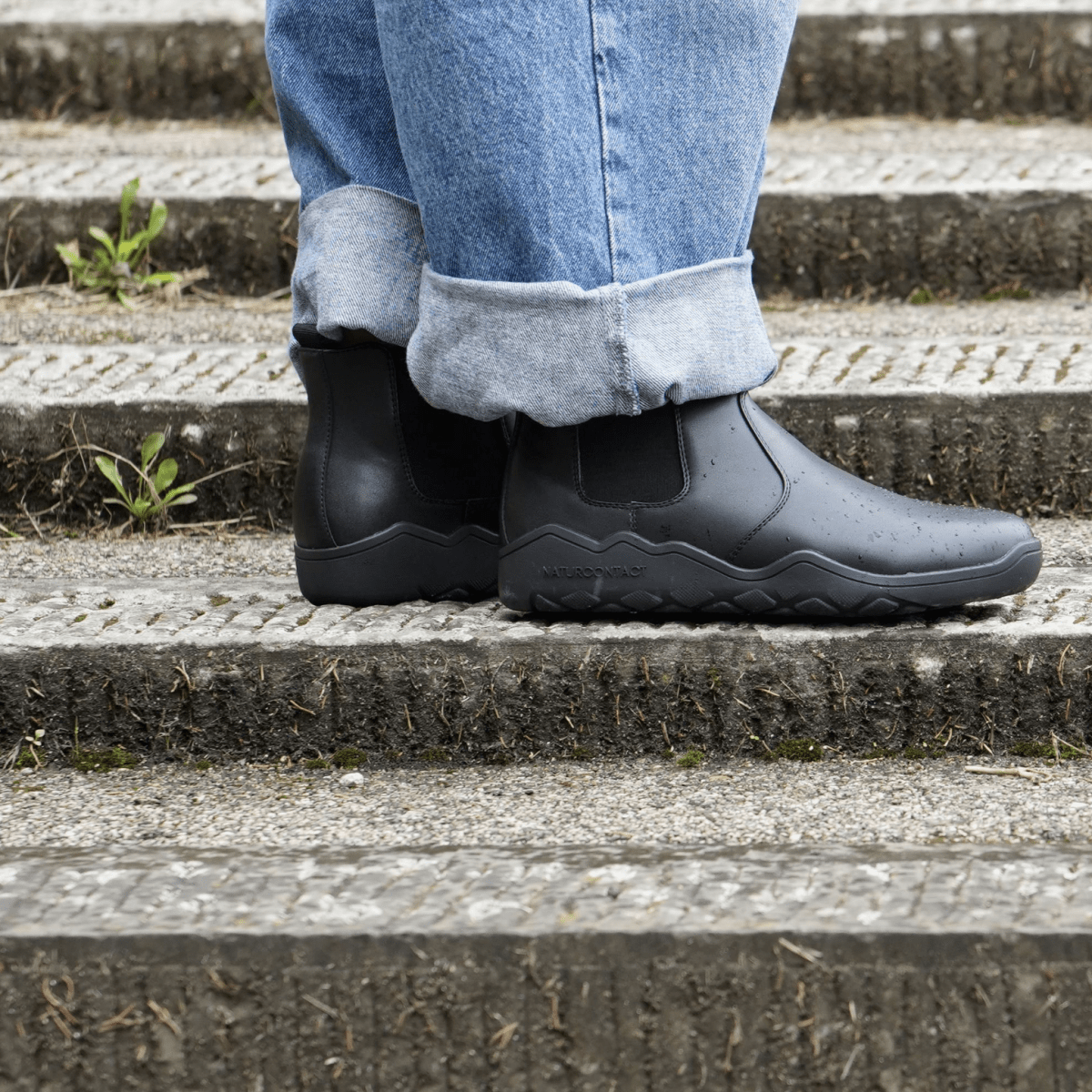side view of Black barefoot chelsea minimalisdt boots on stairs
