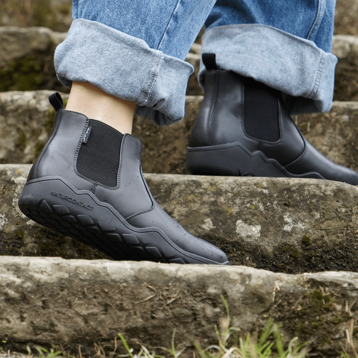 side view of Black barefoot chelsea boots on stairs