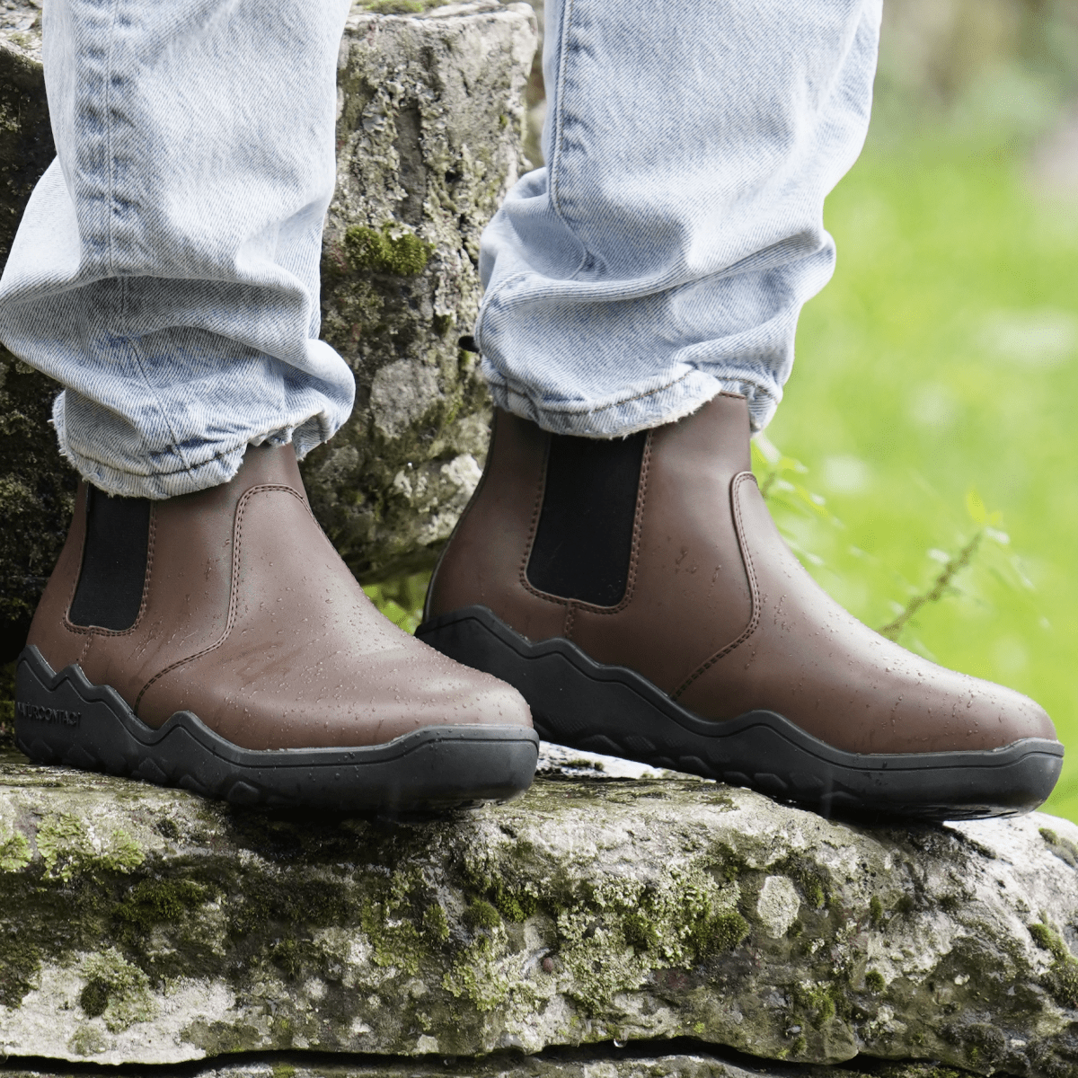 front view of wet Coffee barefoot boots chelsea on a rock worn with jeans