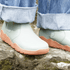 detail of Sage Green barefoot chelsea boots from top with orange sole on a rock