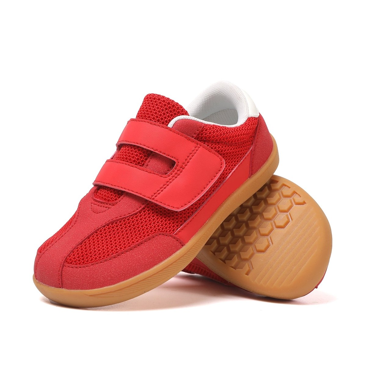 Red barefoot children's sneakers with brown soles on a white background