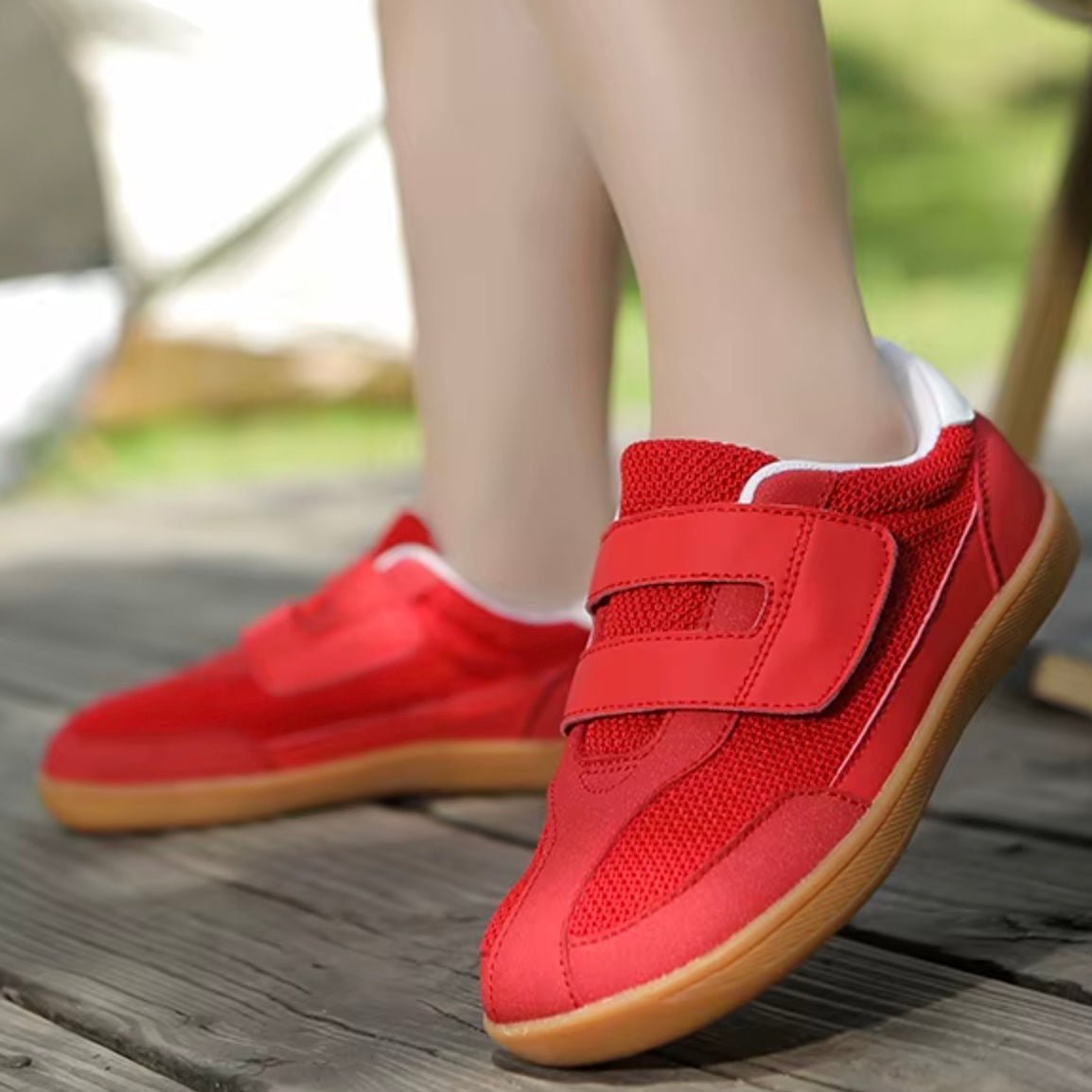 Red barefoot sneakers for kids with velcro straps on a wooden floor