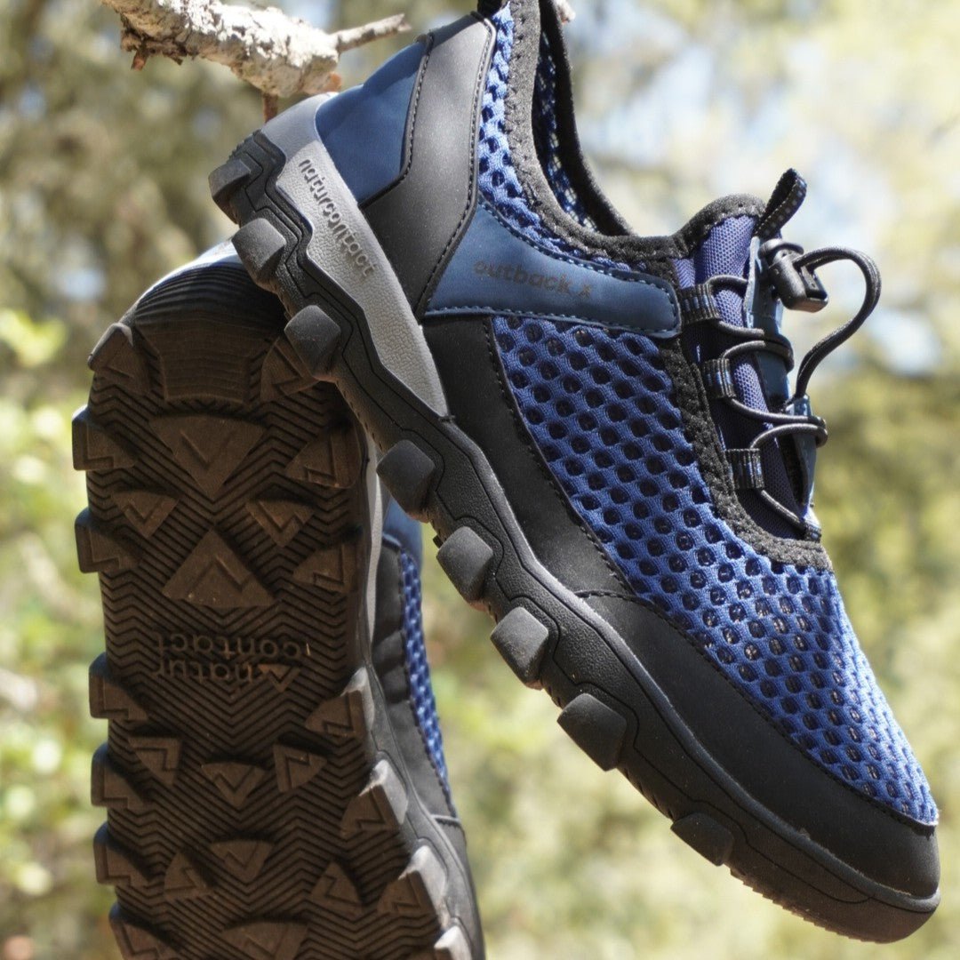 Blue and black hiking shoe with textured sole against a natural background