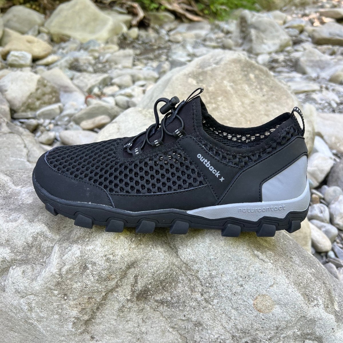 Black hiking barefoot shoe on natural rock landscape