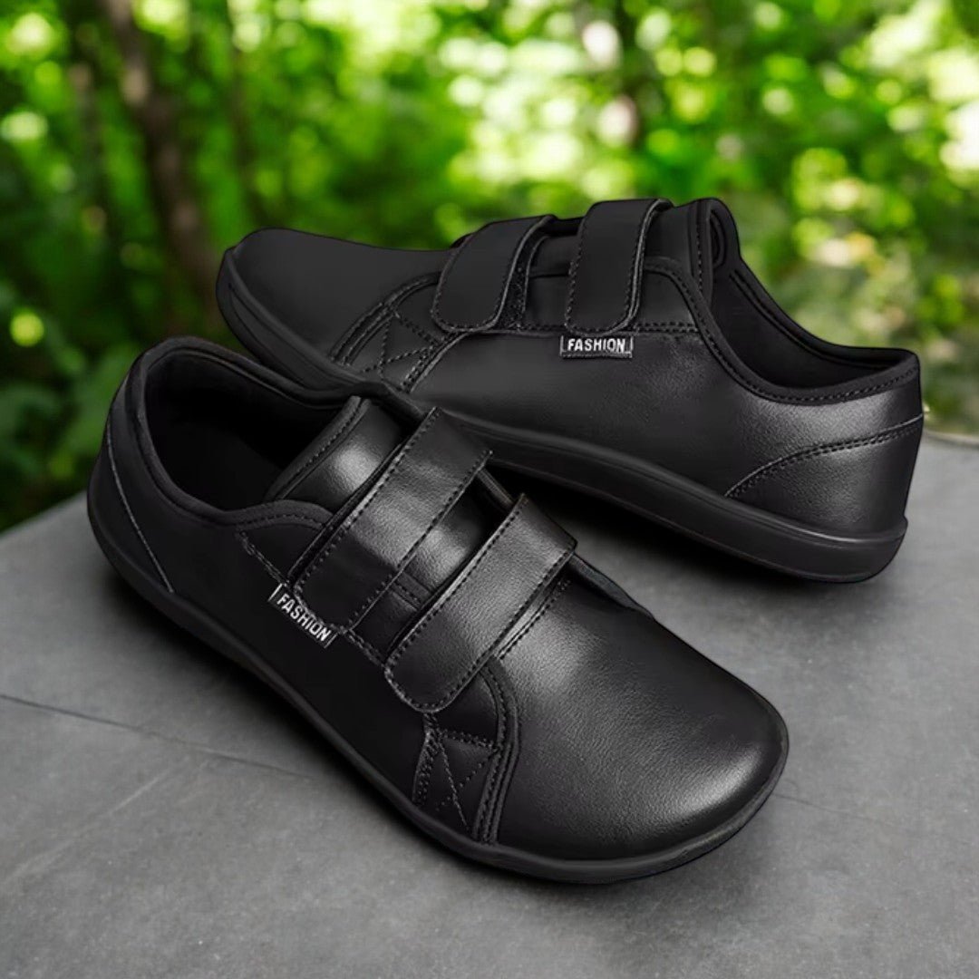 black velcro leather barefoot minimalist shNaturcontact Terra Flex 2.0 barefoot shoes in black, with double velcro straps and wide toe box, shown outdoors in a natural settingoes on a rock