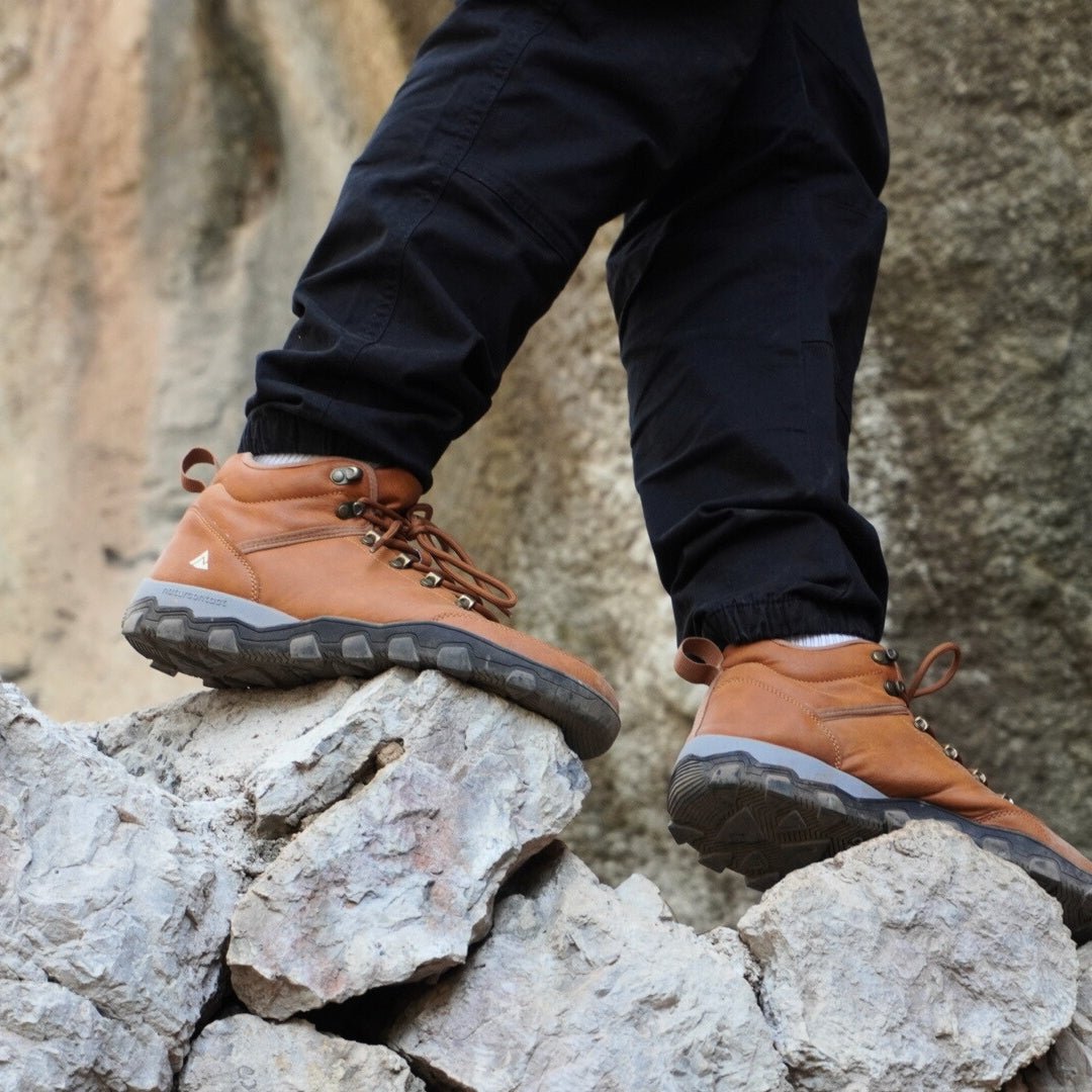 Person wearing tobacco hiking barefoot boots on rocky terrain