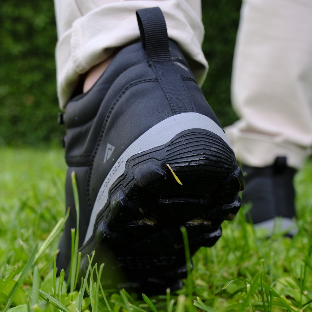 Black shoe with a white sole on grass