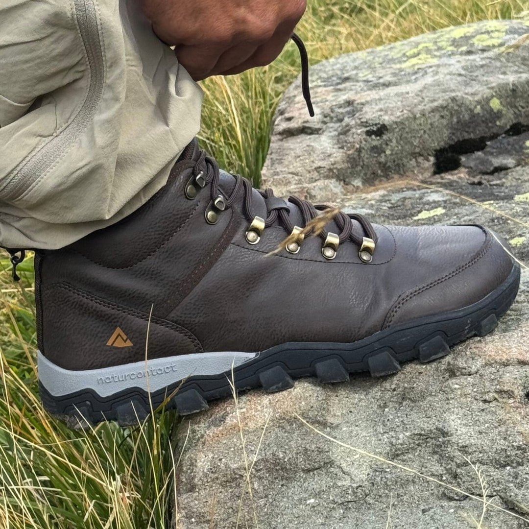 Hiking brown barefoot boot on a rocky ground with grass