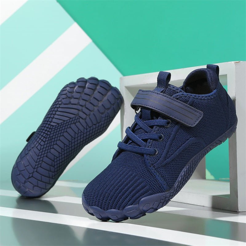 Navy blue athletic barefoot shoes for kids with a textured sole on a geometric background