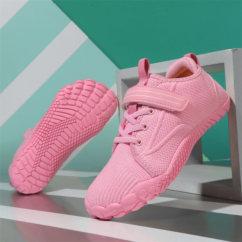 Pink barefoot children's sneakers on a geometric patterned background