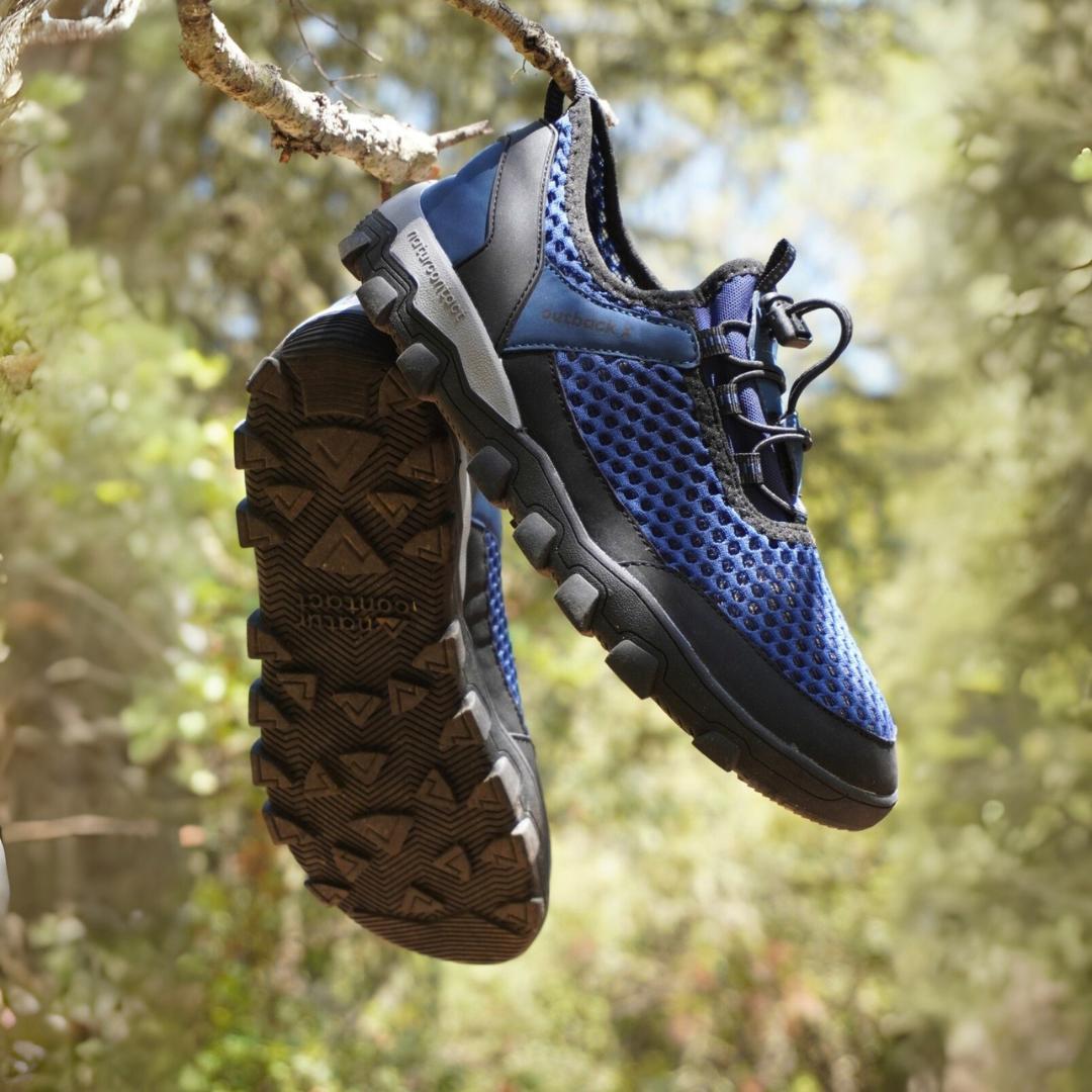 Blue and black Outback X hiking shoes hanging on a tree branch with a natural background