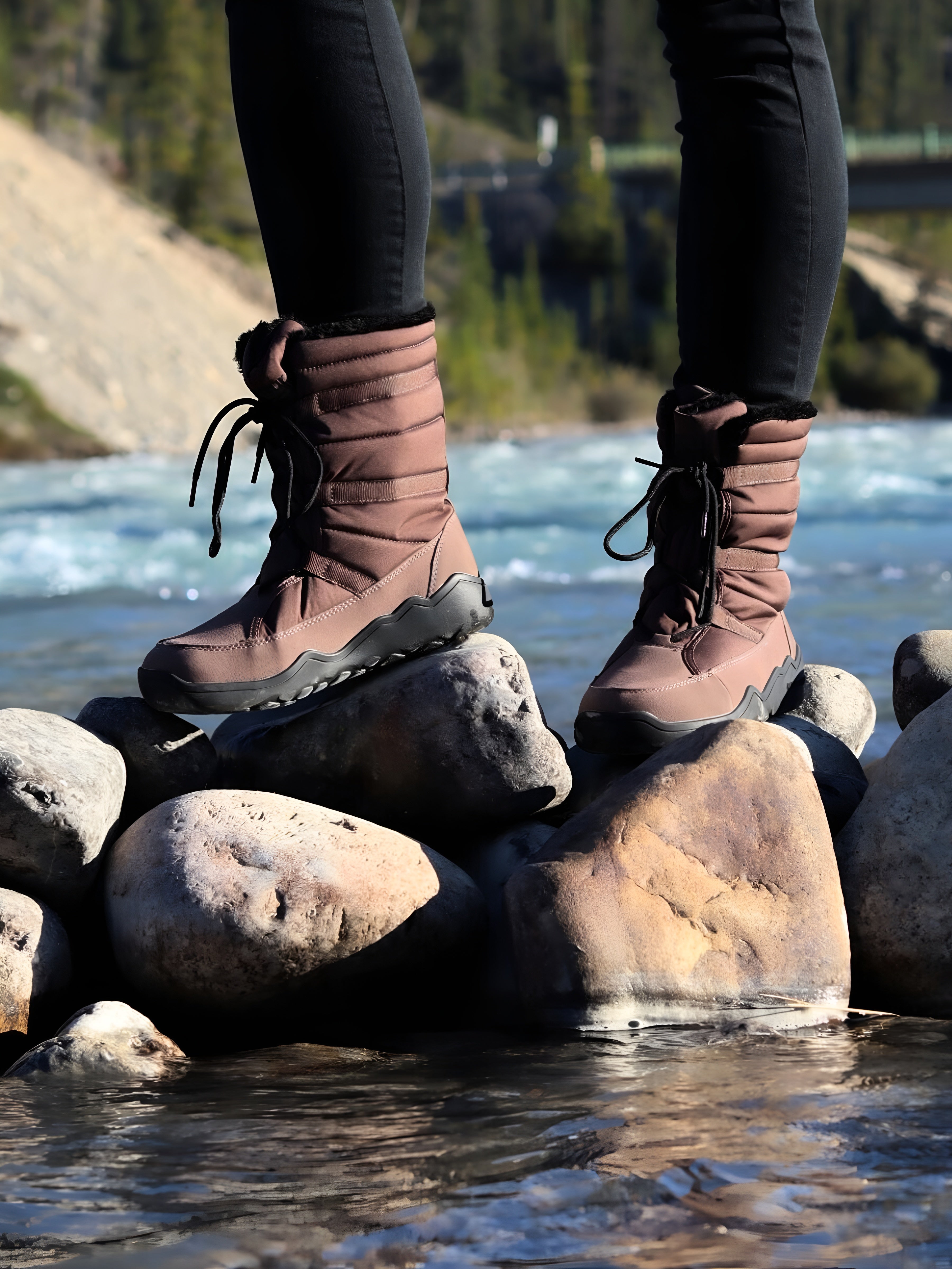 Brown boots on rocks by a body of water with a scenic background