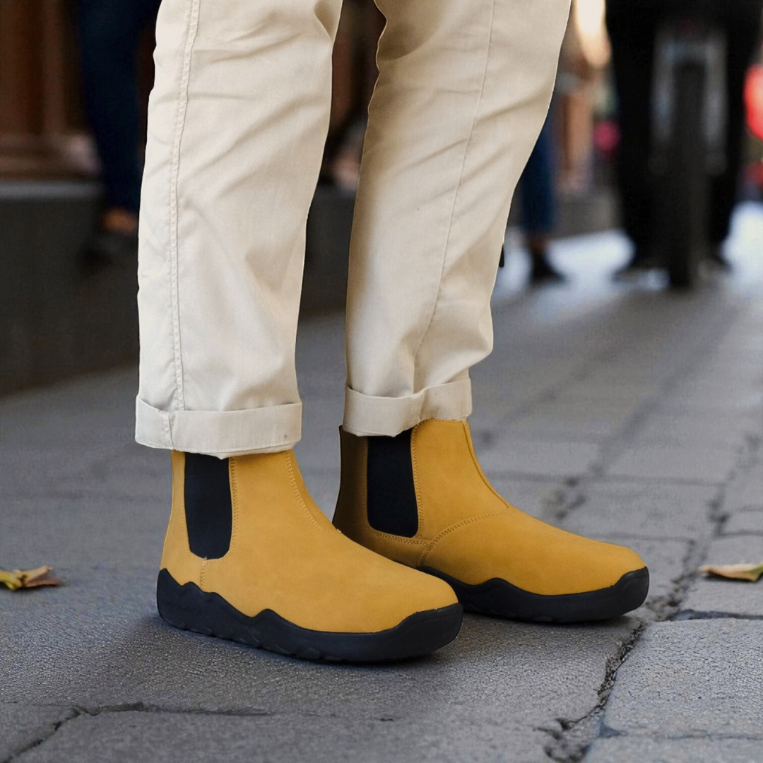 Sand barefoot chelsea boots with black soles worn on a sidewalk
