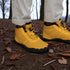 Gold winter boots with black soles worn in a forest setting