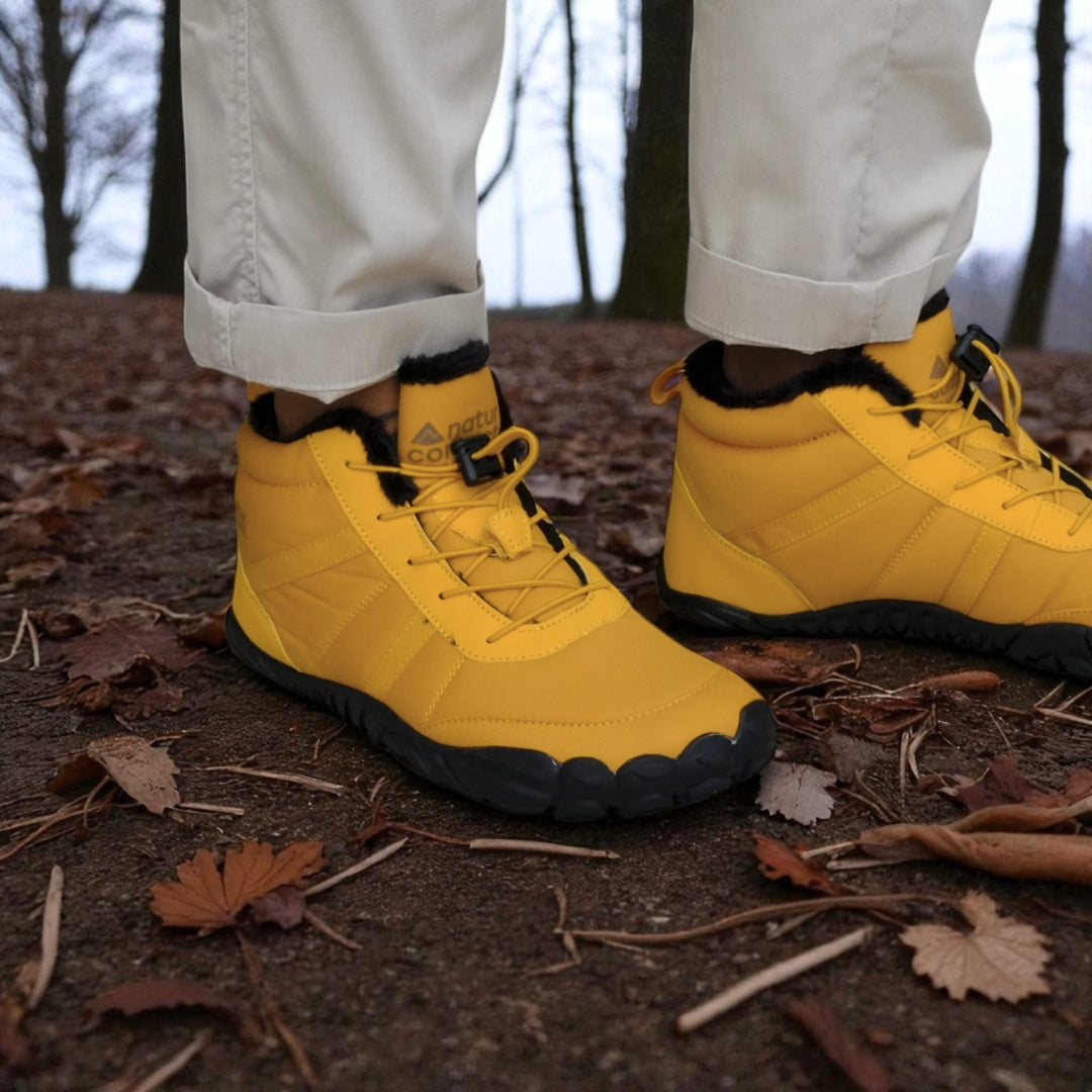 Gold winter boots with black soles worn in a forest setting