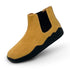Yellow Chelsea boot with black sole on a white background